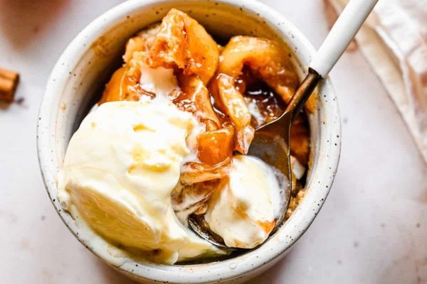 A bowl of apple crisp with ice cream and whipped cream.