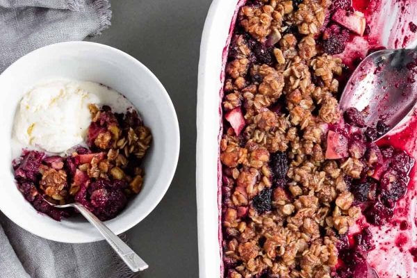 A dish with berries, granola and ice cream.