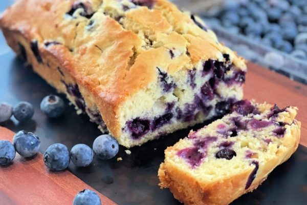 A slice of blueberry bread on a cutting board.