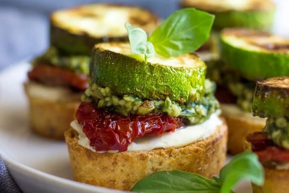 Pesto-infused zucchini bruschetta served on a white plate.
