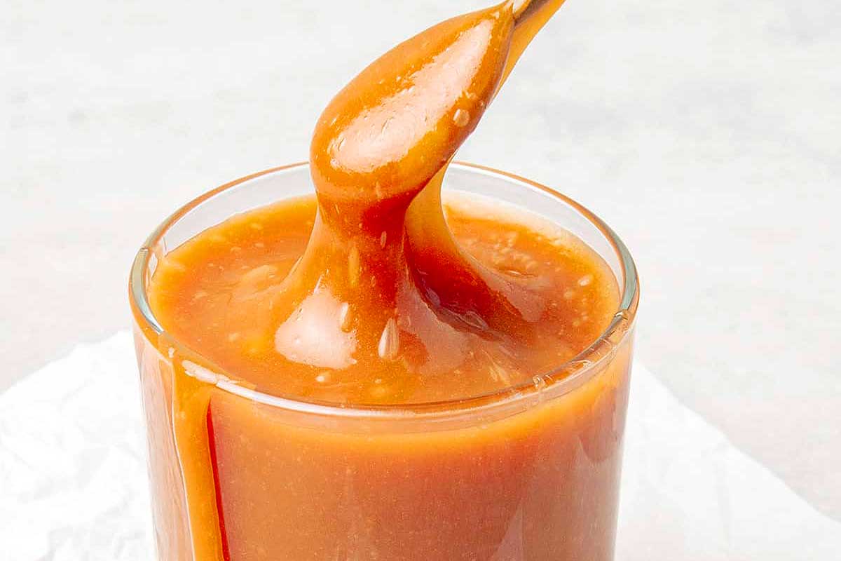 Caramel sauce being poured into a glass.