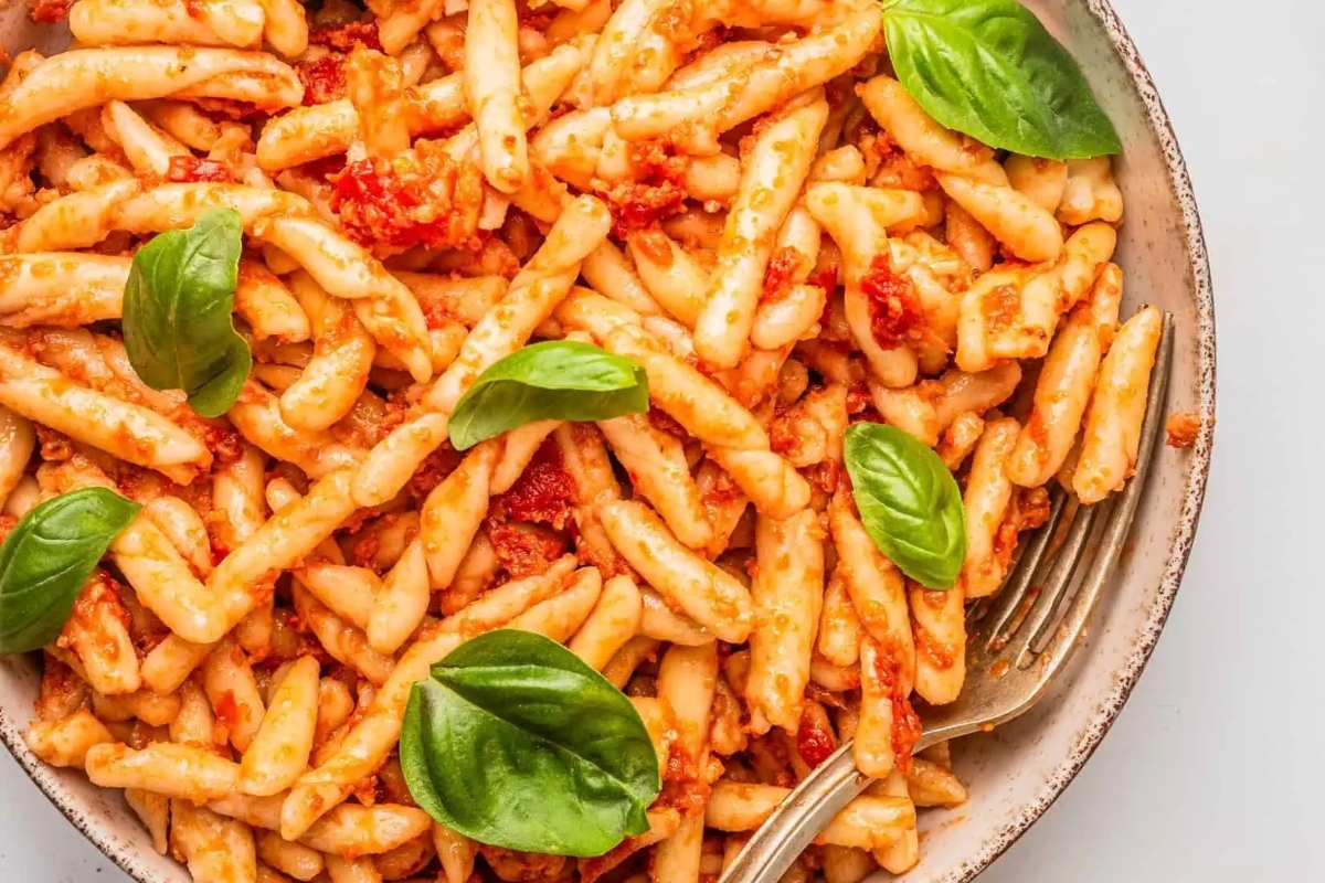 Penne pasta with tomato sauce and basil leaves in a bowl, perfect for homemade pesto recipes.