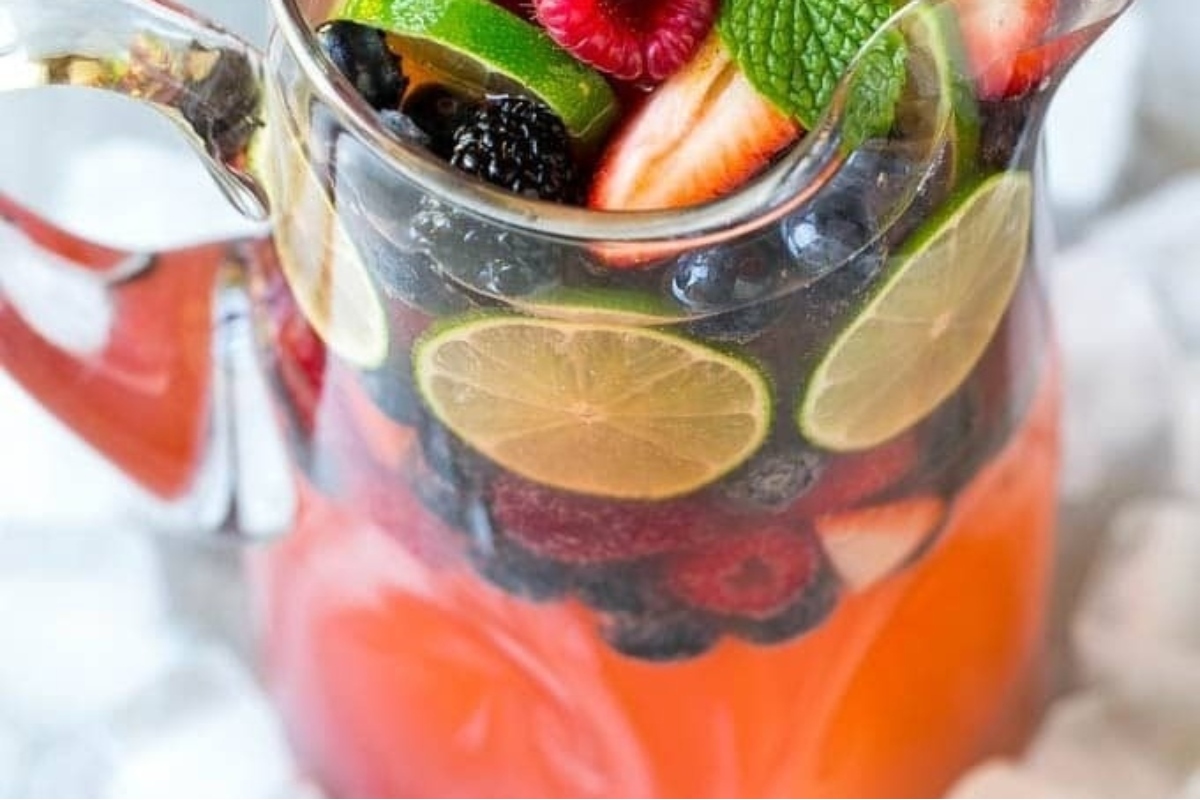 A pitcher filled with refreshing cocktails made from berries and limes.