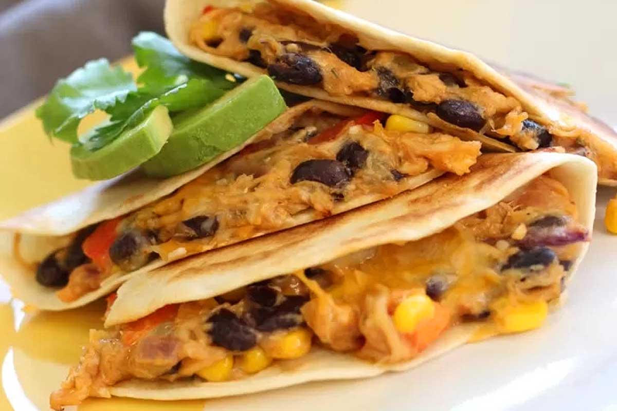 Chicken quesadillas with black beans and avocado on a plate.
