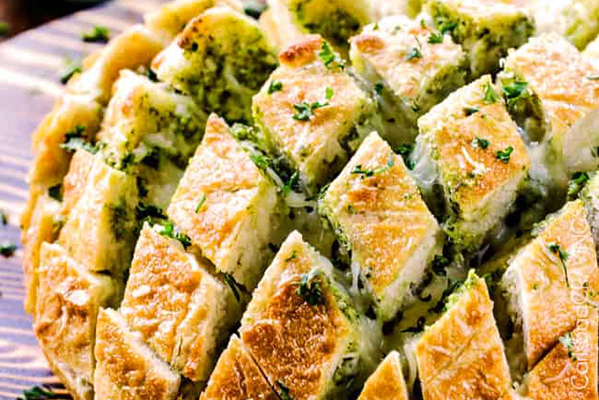 A flavorful loaf of bread topped with cheese, herbs, and a touch of pesto.