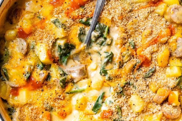 Cheesy spinach and mushroom casserole in a pan with a spoon.