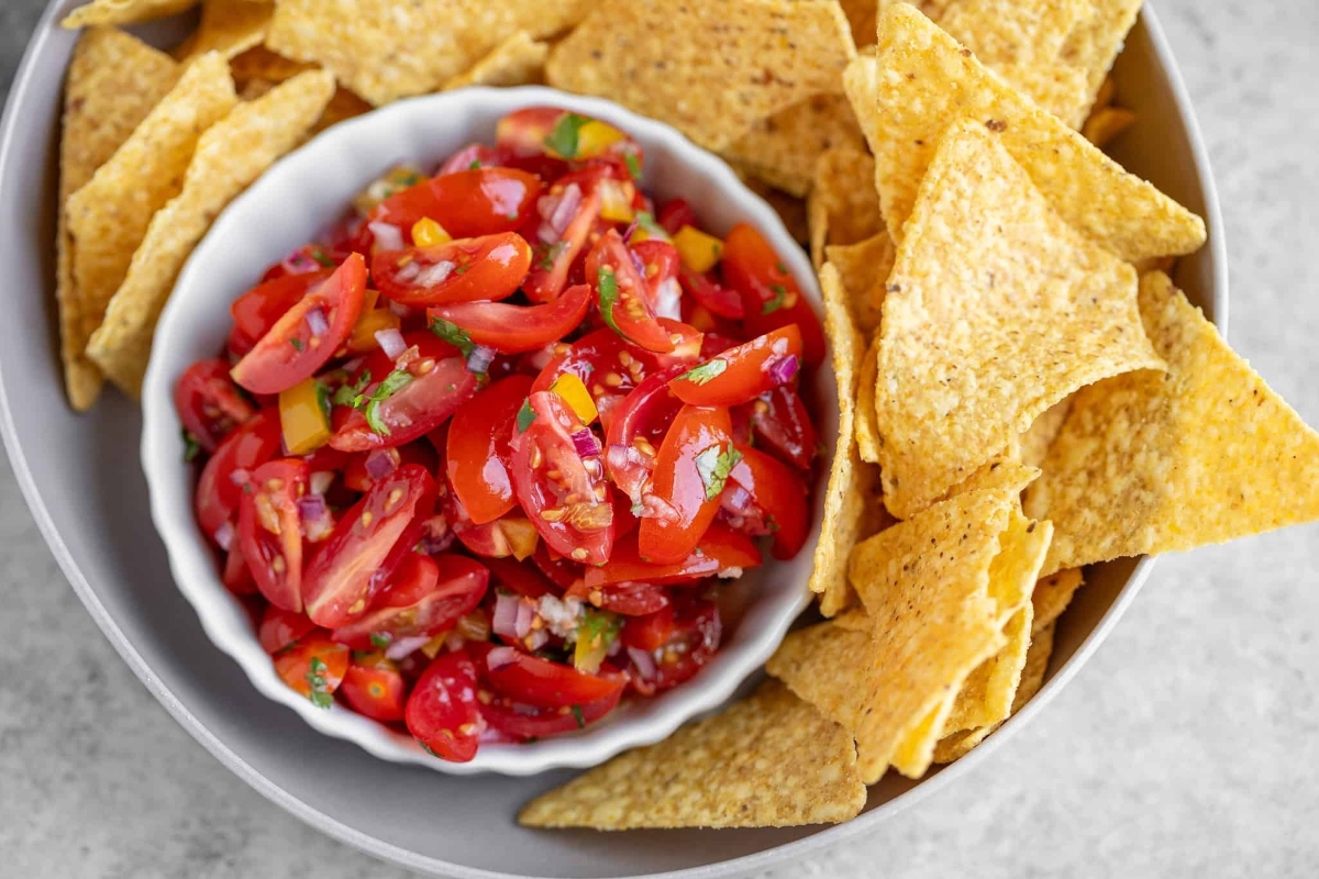 A bowl of tomato salsa with tortilla chips.
