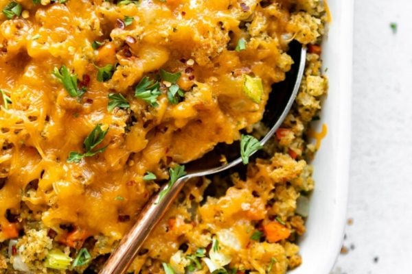 A casserole dish with a spoonful of cheesy stuffing.