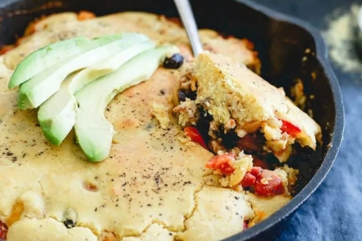 Savoury Mexican cornbread pie in a skillet with avocado.