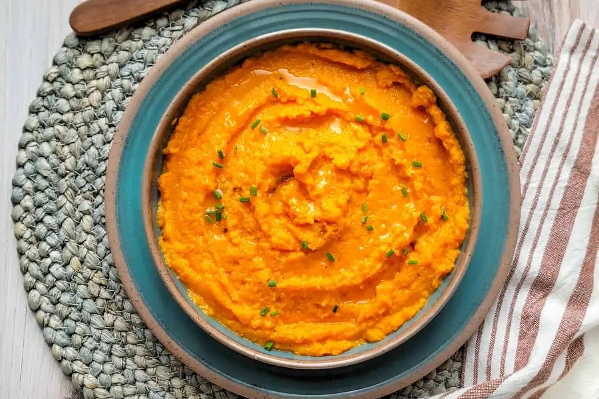 A bowl of sweet potato mashed potatoes on a table, served as a flavorful side dish.