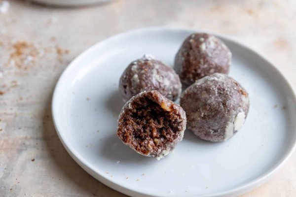 Traditional chocolate protein balls on a plate with a bite taken out.