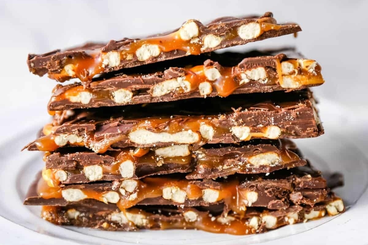 A stack of chocolate caramel bars, resembling a delectable Christmas bark, on a white plate.