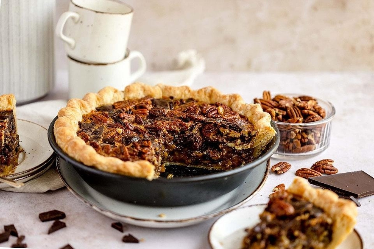Pecan pie with chocolate and pecans on a plate.