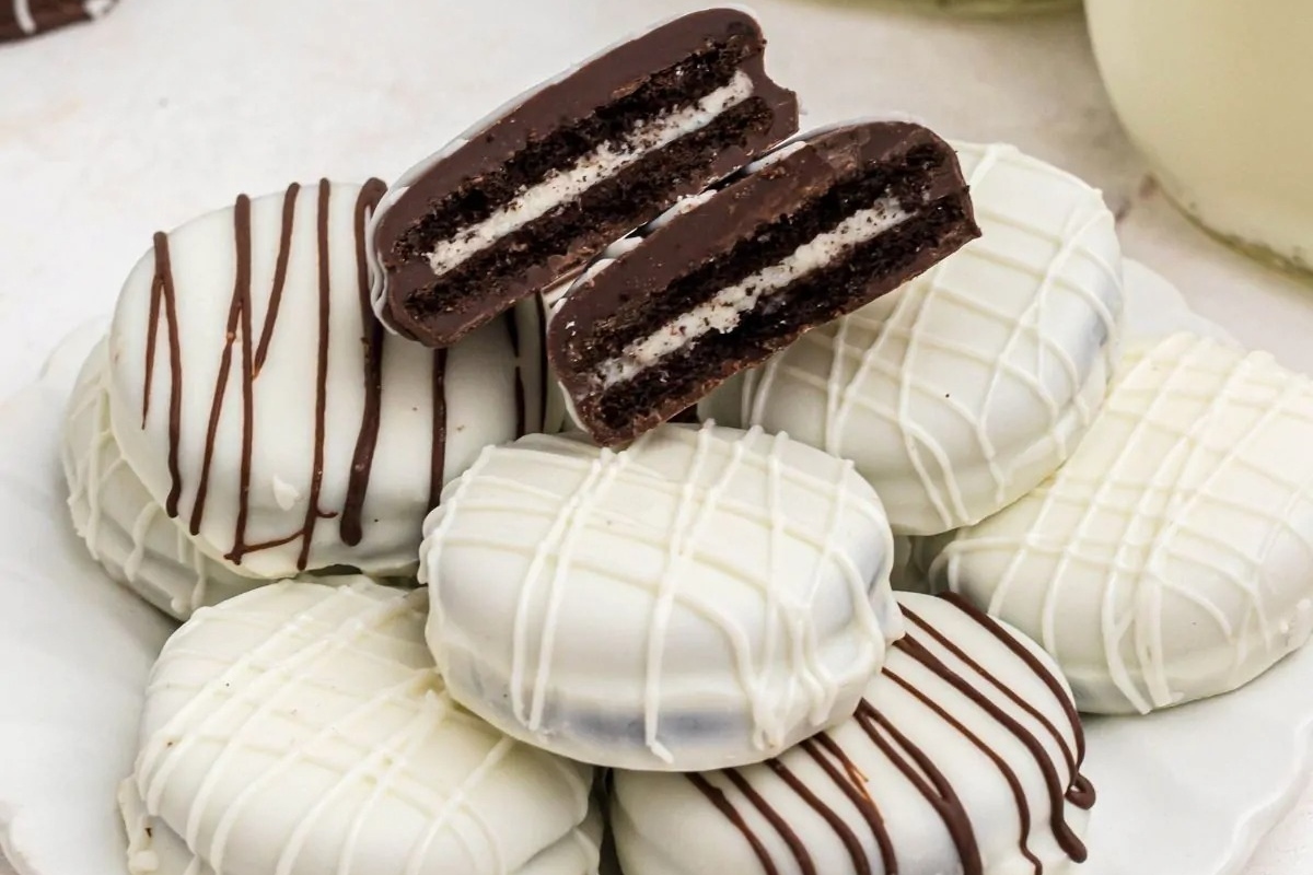 No-bake Oreo cookies on a white plate with a glass of milk, perfect for holiday desserts.