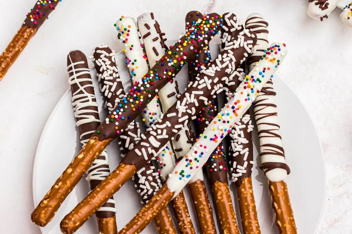 White chocolate covered pretzels with sprinkles on a plate, prepared using a recipe.