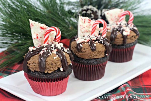 Three Christmas cupcakes with candy canes on a plate.