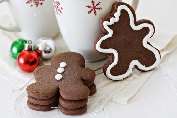 Christmas-themed gingerbread cookies on a table next to a cup of coffee.