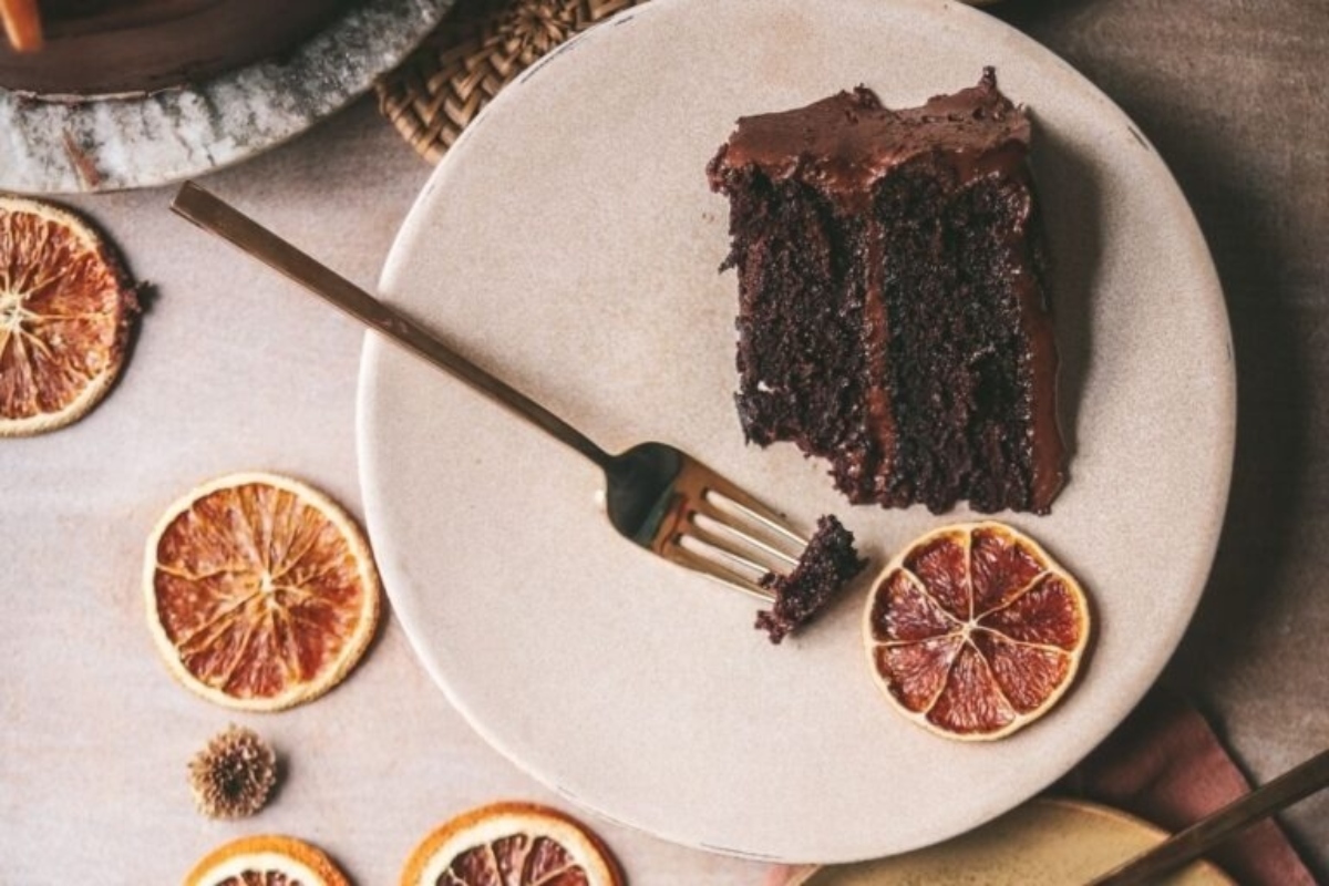 A slice of chocolate cake with orange slices on a plate, perfect for Christmas celebrations.