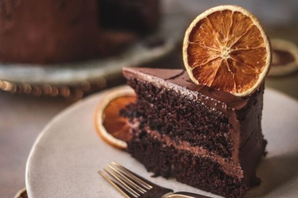 A slice of chocolate cake with orange slices on a plate.