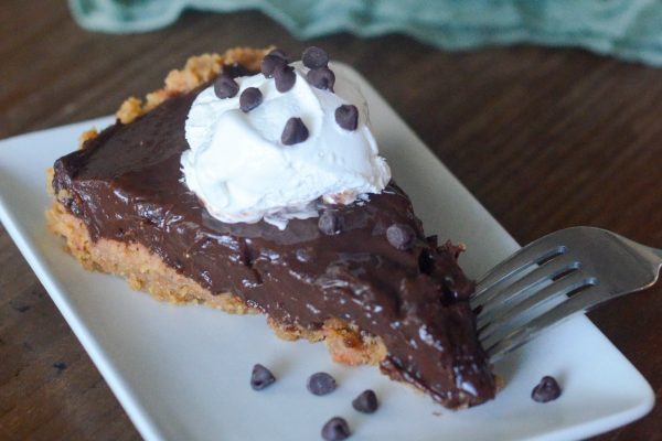 A decadent slice of chocolate pie, generously topped with fluffy whipped cream and sprinkled with delectable chocolate chips.