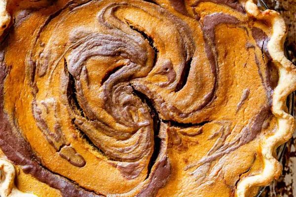 A pumpkin pie with a chocolate swirl on top.
