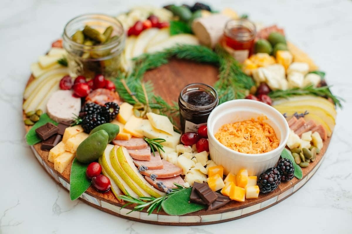 A Christmas-themed wooden platter with a variety of charcuterie and fruits, beautifully arranged on boards.