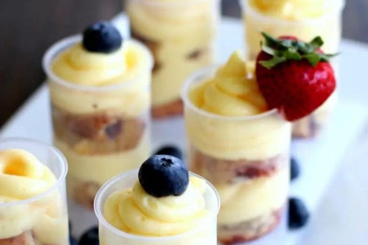 A tray of mini desserts with blueberries and lemons, including cinnamon rolls.