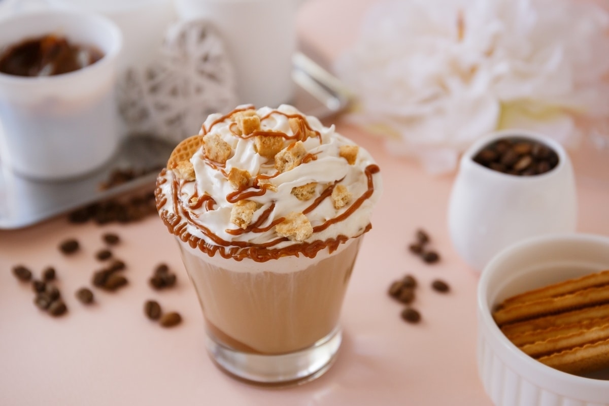 A holiday-inspired cup of coffee with whipped cream and cinnamon sticks.