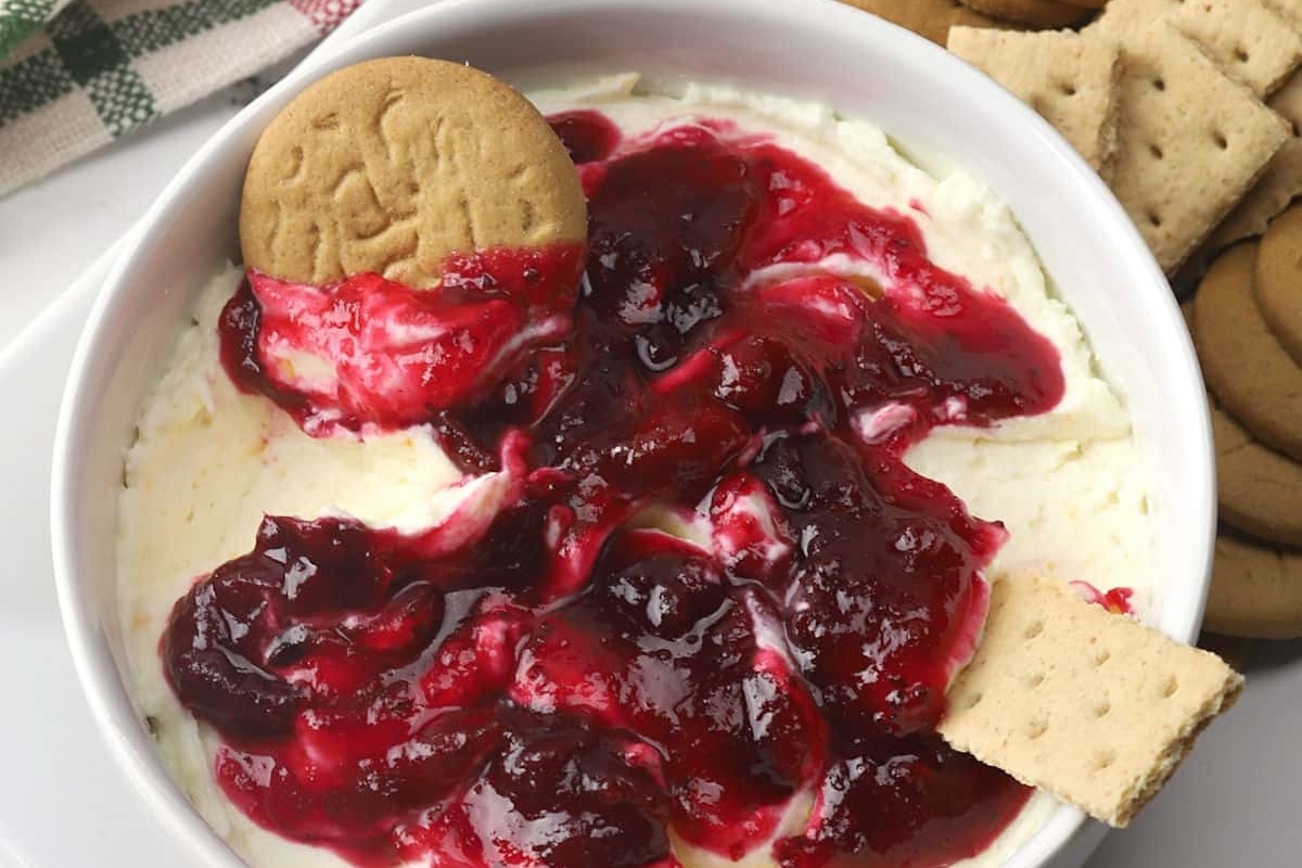 A festive holiday cranberry dip paired with crispy crackers and topped with a dollop of tangy cranberry sauce.