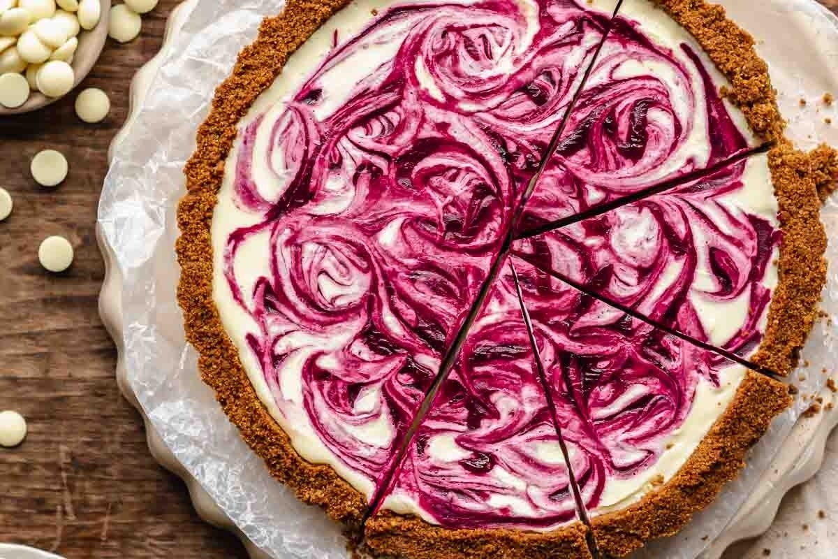 A delicious recipe for a white chocolate and raspberry cheesecake, complete with a tantalizing slice taken out.