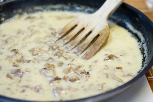 A bowl of mushroom sauce with a wooden spoon, perfect for creamy soups.