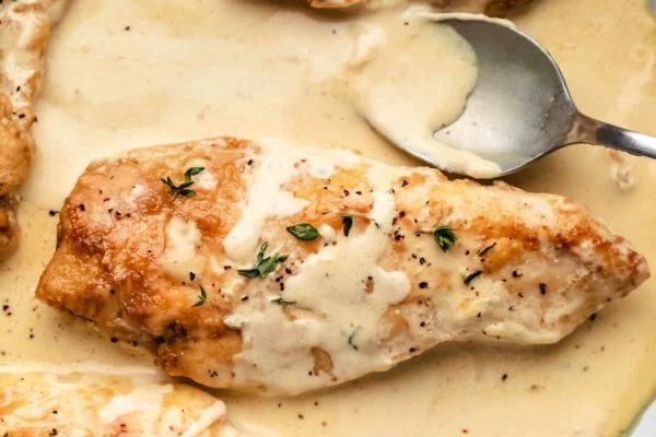 Chicken breasts in a creamy sauce with a spoon.