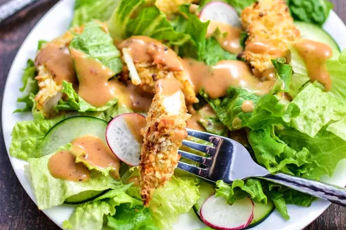 A salad with chicken and radishes on a plate.