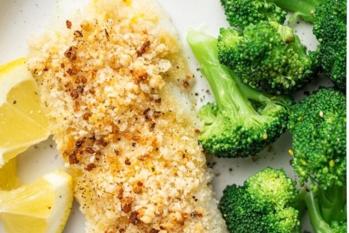 Feast of seven fishes featuring fish fillet with broccoli and lemon slices on a plate.
