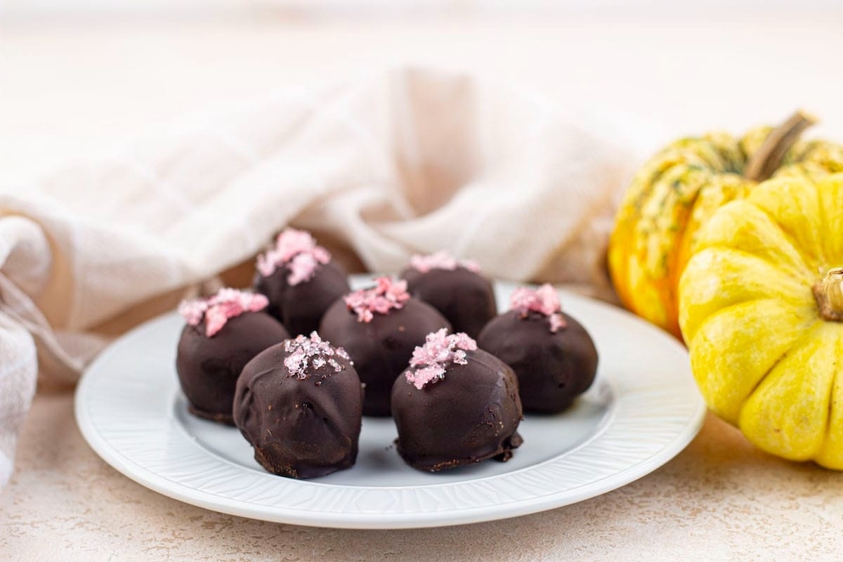 No Bake Chocolate Truffles on a plate next to pumpkins, perfect for holiday desserts.