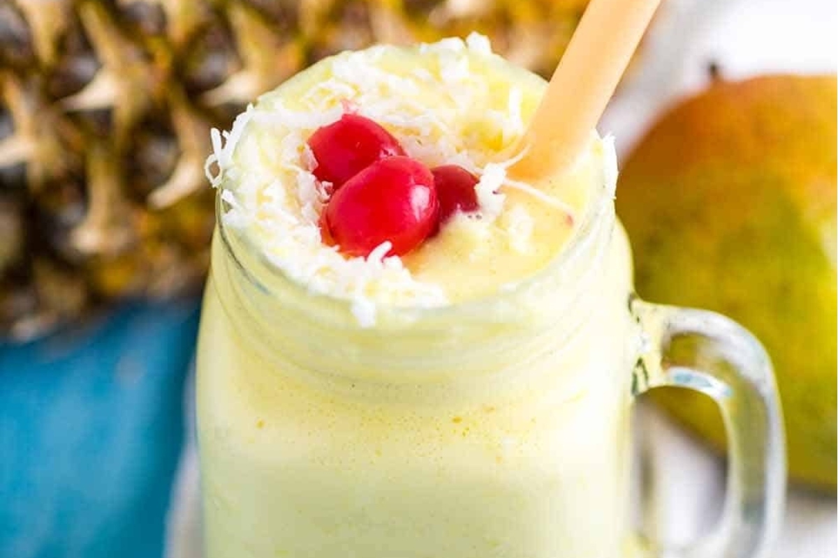 An inspired Hawaiian coconut milk smoothie with cherries and pineapples in a mason jar.
