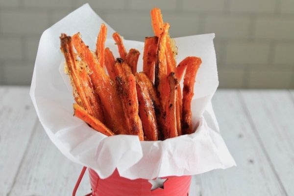 Carrot fries in a red bucket on a table.