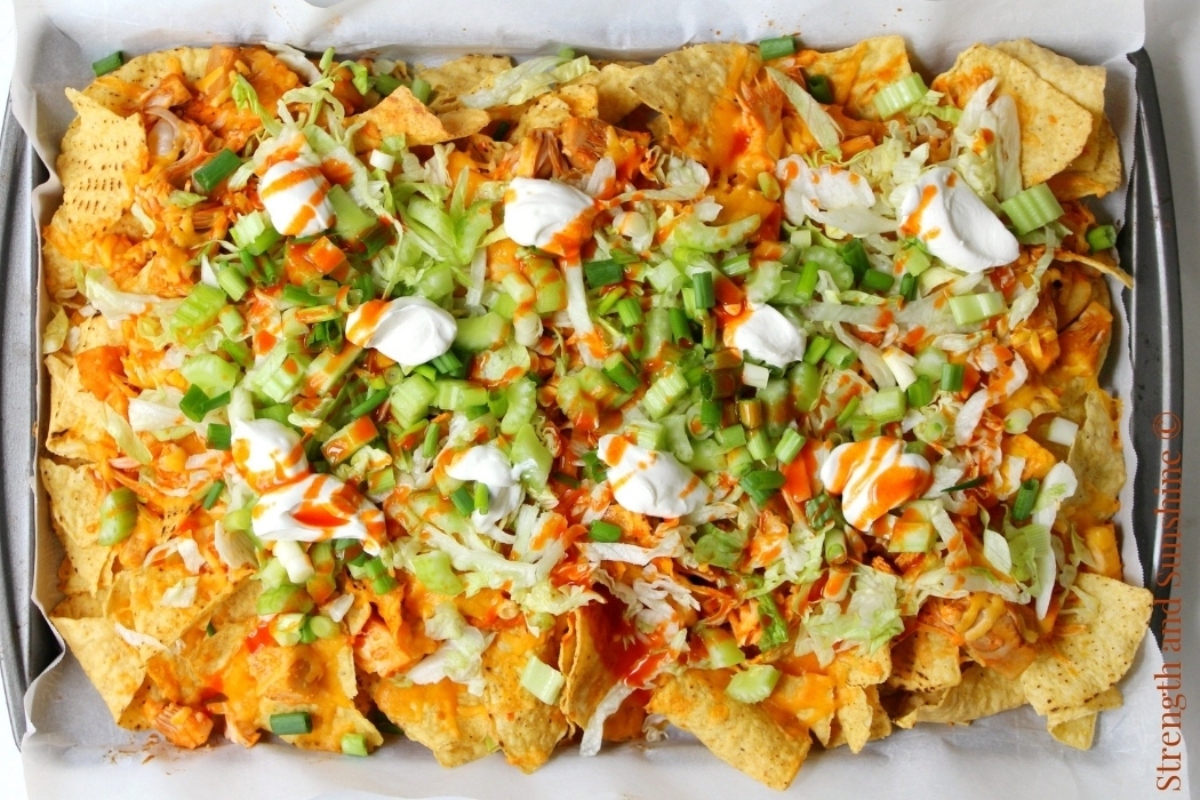 A tray of nachos with sour cream and sour cream.