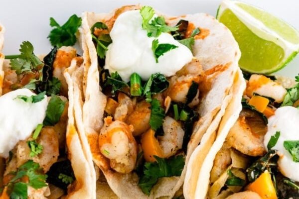 Shrimp tacos with sour cream and lime on a plate.