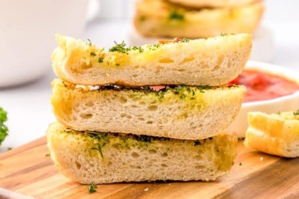 A stack of garlic bread on a wooden cutting board.