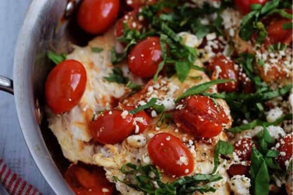 Chicken with tomatoes and herbs in a skillet.