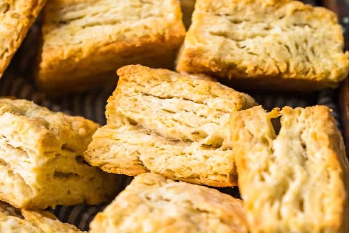 A stack of biscuits on a baking sheet, ready to be served in a bread basket.
