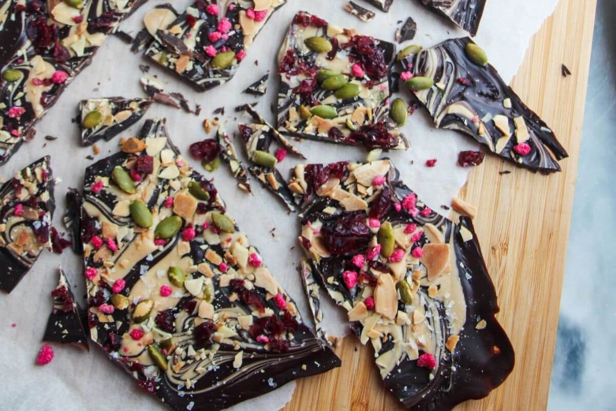 White chocolate bark with cranberries and nuts on a cutting board.