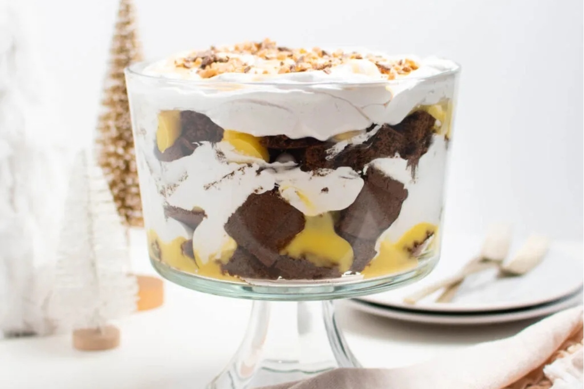 An exquisitely presented trifle in a glass bowl, adorned with fluffy whipped cream and tantalizing slices of bananas.