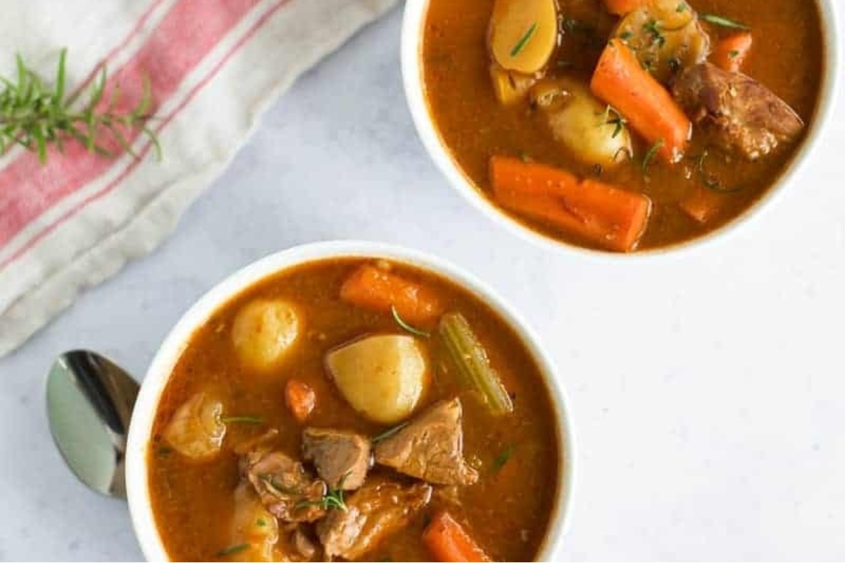 Two bowls of beef stew with potatoes and carrots.