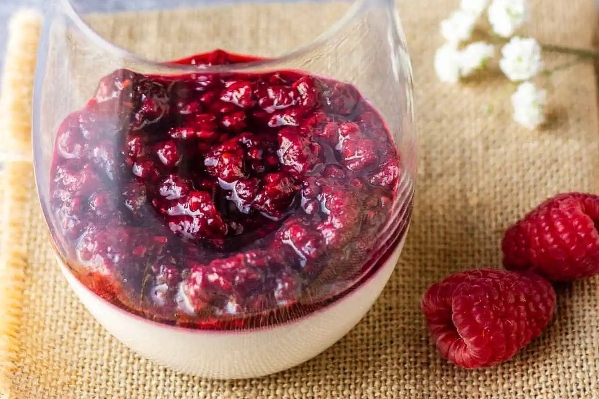 An Italian dessert recipe featuring a glass with raspberries and yogurt in it.