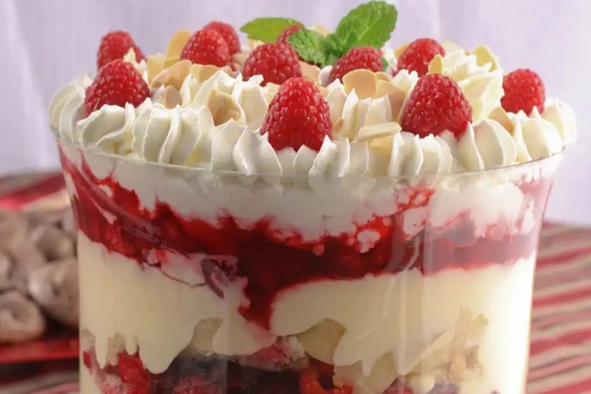 A festive Christmas trifle with raspberries and cream in a glass.
