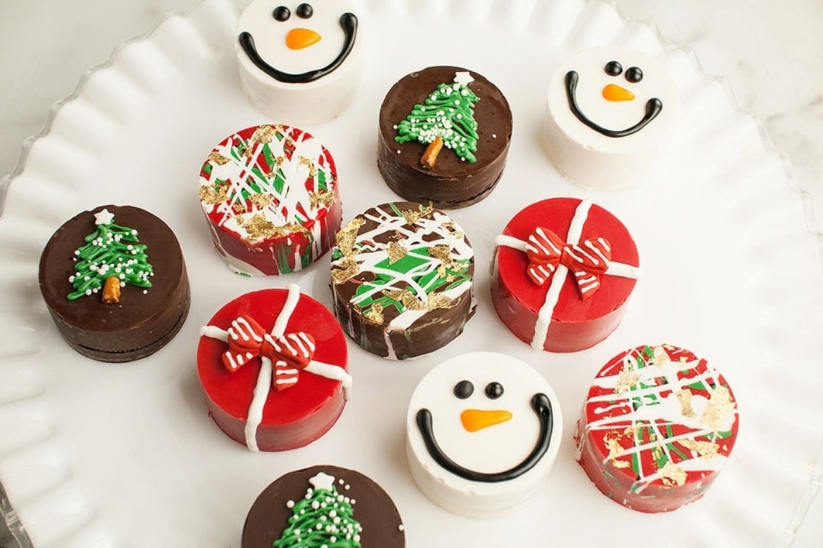 A plate of chocolate Christmas cookies decorated with snowmen and Christmas trees.
