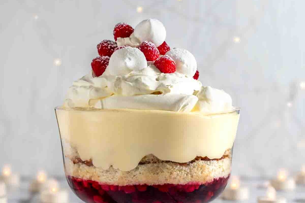 A Christmas trifle in a glass with whipped cream and raspberries.