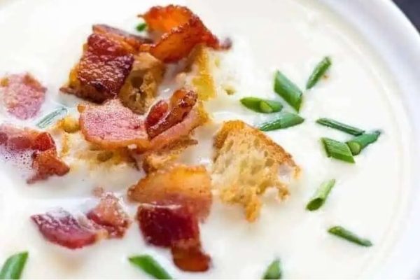 A creamy bowl of soup with bacon and croutons.